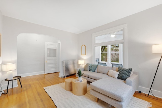 1925 Glenwood Ave, Minneapolis, MN 55405 - living room featuring radiator heating unit, arched walkways, light wood-style flooring, and baseboards