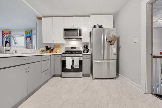 1925 Glenwood Ave, Minneapolis, MN 55405 - kitchen featuring appliances with stainless steel finishes, gray cabinets, light countertops, light marble finish flooring, and baseboards
