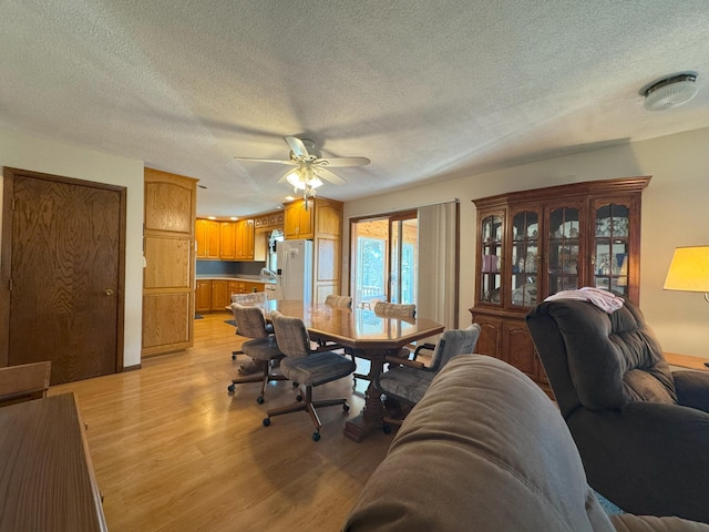 dining room with light wood finished floors, ceiling fan, and a textured ceiling