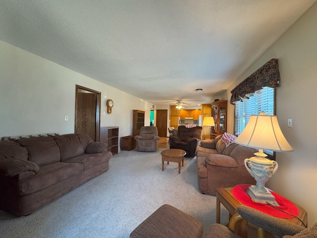 living area with light colored carpet, a ceiling fan, and a textured ceiling