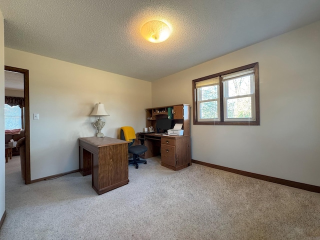 office space featuring light colored carpet, baseboards, and a textured ceiling