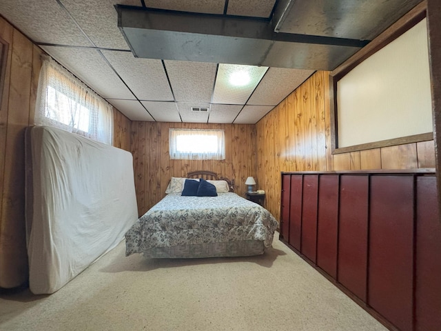 bedroom featuring carpet floors, wood walls, and a drop ceiling