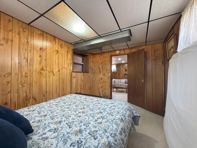 bedroom featuring carpet flooring, wood walls, and a paneled ceiling