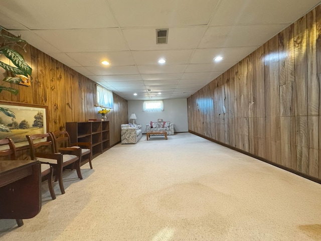 sitting room featuring wooden walls, carpet, recessed lighting, and a drop ceiling