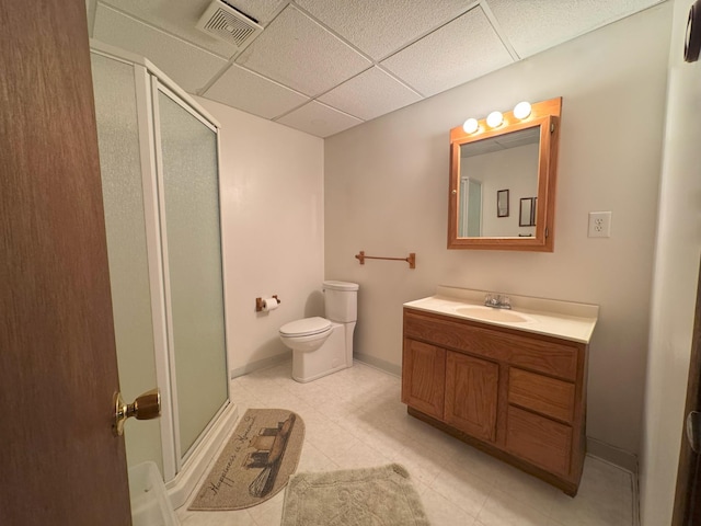 bathroom featuring a shower stall, vanity, toilet, a paneled ceiling, and baseboards