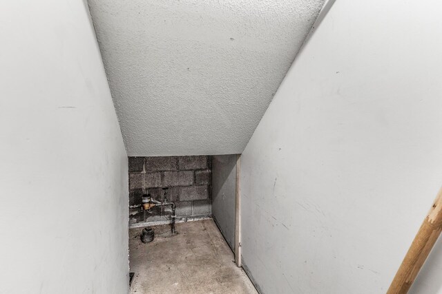 1260 Ferndale St N, Maplewood, MN 55119 - stairs with concrete flooring, a textured ceiling, and concrete block wall