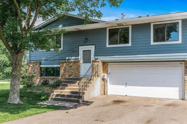 1260 Ferndale St N, Maplewood, MN 55119 - view of front facade featuring an attached garage, asphalt driveway, and stone siding