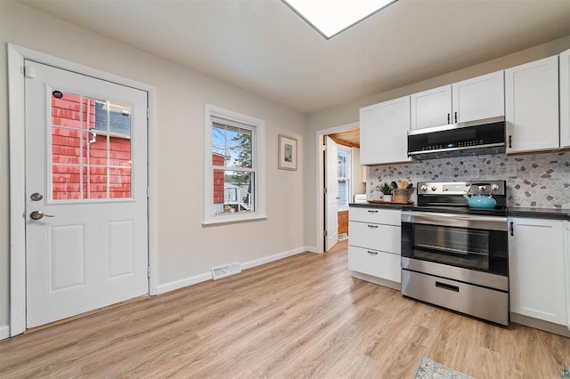 kitchen featuring dark countertops, light wood-style floors, white cabinetry, backsplash, and appliances with stainless steel finishes
