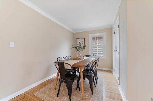 dining space with baseboards, light wood finished floors, and crown molding