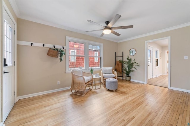 living area featuring light wood finished floors, crown molding, baseboards, and a ceiling fan