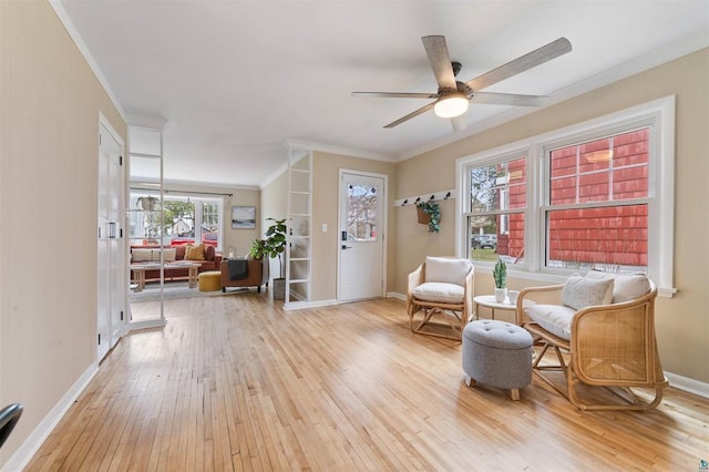 sitting room with crown molding, baseboards, a ceiling fan, and wood-type flooring