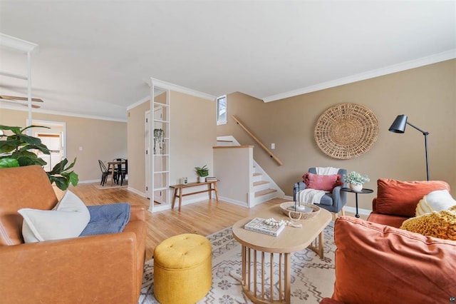 living room with crown molding, stairs, baseboards, and wood finished floors