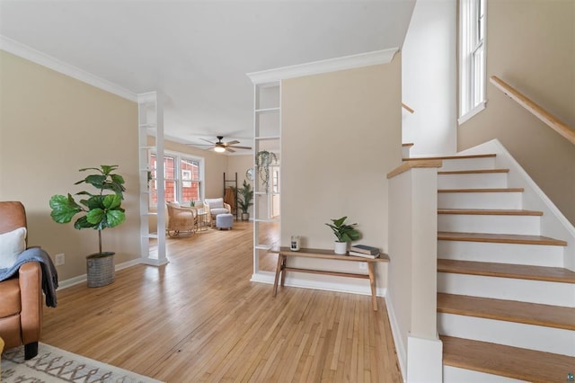 interior space with ornamental molding, baseboards, a ceiling fan, and wood finished floors
