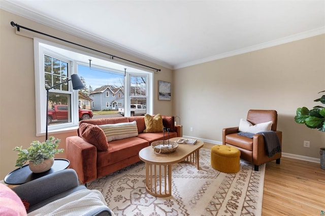 living area with crown molding, baseboards, and light wood-style floors