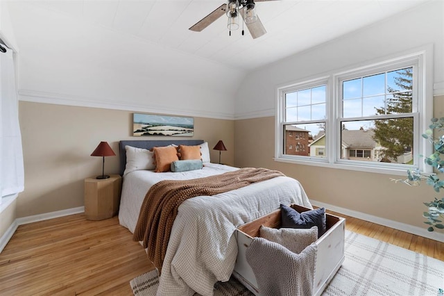 bedroom with light wood finished floors, vaulted ceiling, baseboards, and ceiling fan