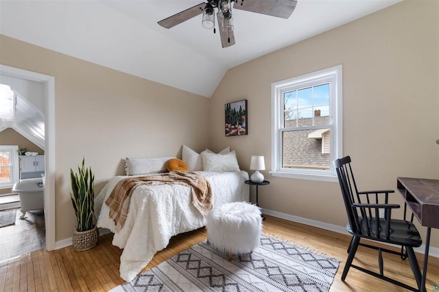 bedroom featuring baseboards, light wood-type flooring, and vaulted ceiling