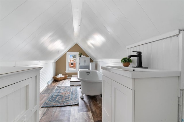 full bath with vanity, hardwood / wood-style flooring, lofted ceiling, and a freestanding bath