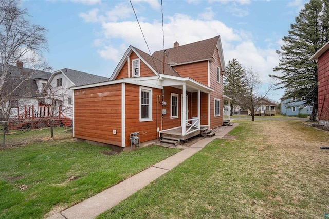 view of front of house featuring a front lawn, roof with shingles, and a chimney
