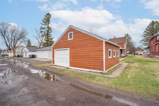 view of property exterior featuring a lawn, an outbuilding, and a detached garage