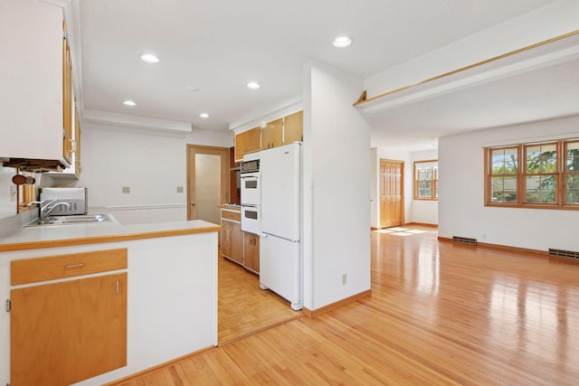 kitchen featuring a sink, visible vents, white appliances, light countertops, and light wood-style floors