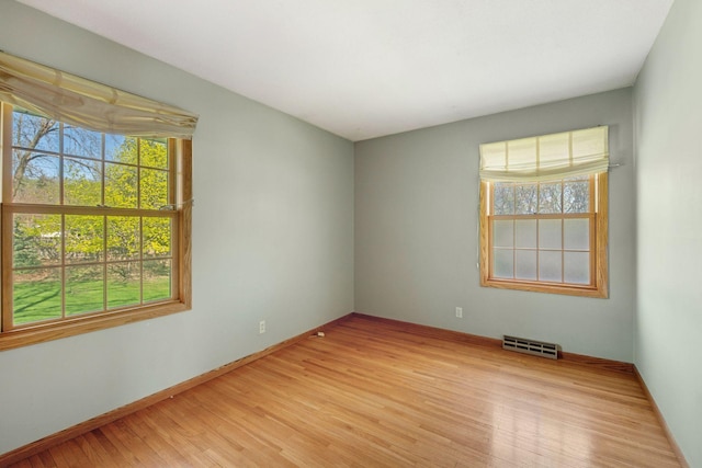 unfurnished room with baseboards, light wood-type flooring, and visible vents