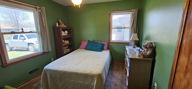 carpeted bedroom featuring multiple windows and baseboards