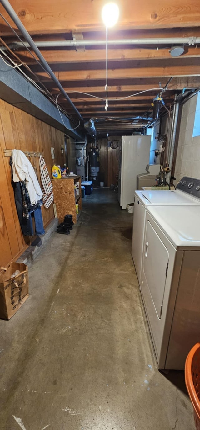 unfinished below grade area featuring washer and dryer, refrigerator, and water heater