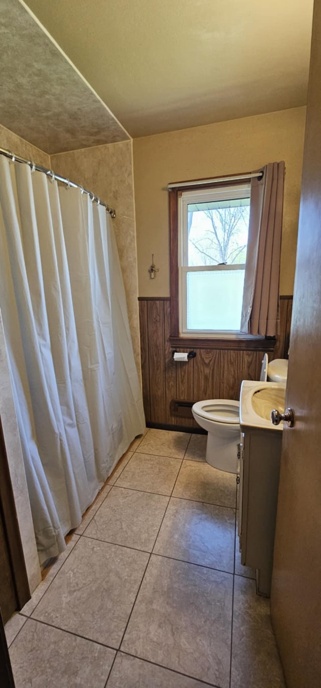 bathroom featuring toilet, wainscoting, vanity, tile patterned floors, and a shower with curtain