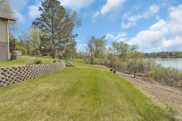 view of green lawn featuring a water view and stairway