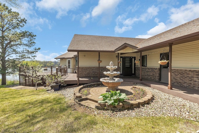 22 13th St S, Sauk Rapids, MN 56379 - back of house featuring brick siding, roof with shingles, a lawn, and a wooden deck