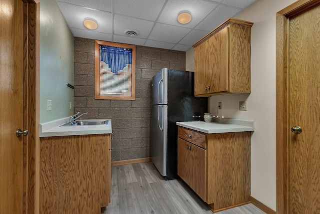 22 13th St S, Sauk Rapids, MN 56379 - kitchen featuring a sink, light wood-style flooring, a paneled ceiling, freestanding refrigerator, and light countertops