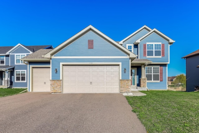 7145 208th Cv N, Forest Lake, MN 55025 - craftsman-style house featuring a garage, asphalt driveway, stone siding, and a front yard