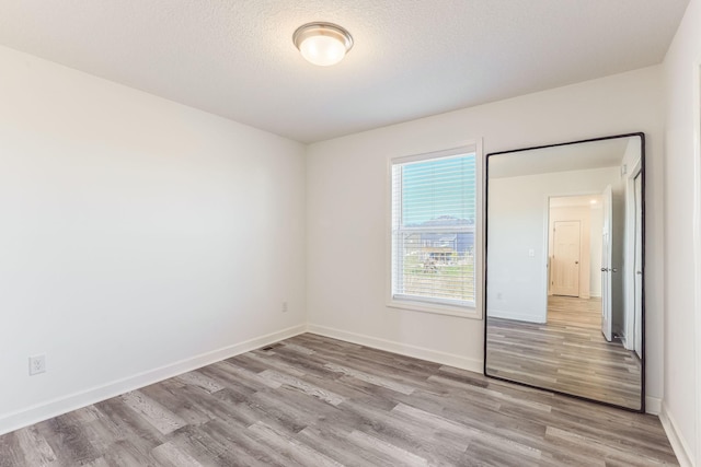 7145 208th Cv N, Forest Lake, MN 55025 - unfurnished bedroom with light wood finished floors, baseboards, and a textured ceiling