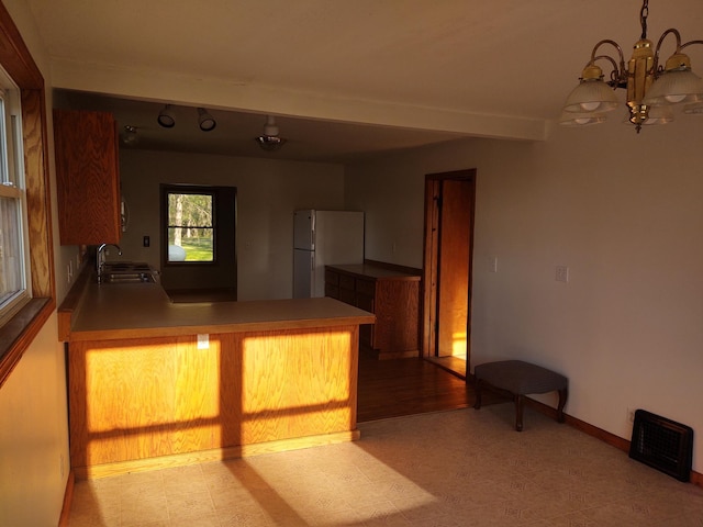36998 Quest Rd, Hillman, MN 56338 - kitchen with freestanding refrigerator, a chandelier, a peninsula, a sink, and baseboards