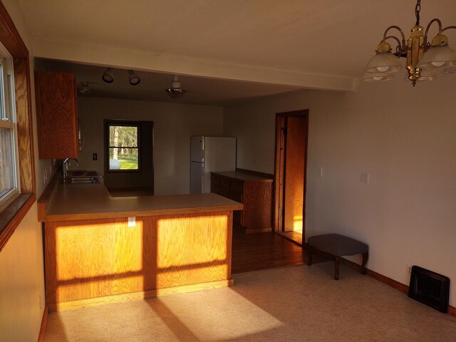 36998 Quest Rd, Hillman, MN 56338 - kitchen with freestanding refrigerator, a chandelier, a peninsula, and light flooring