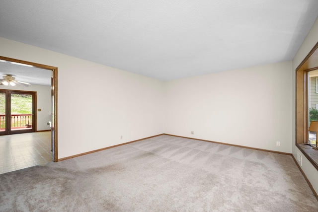 unfurnished room with baseboards, a ceiling fan, and light colored carpet
