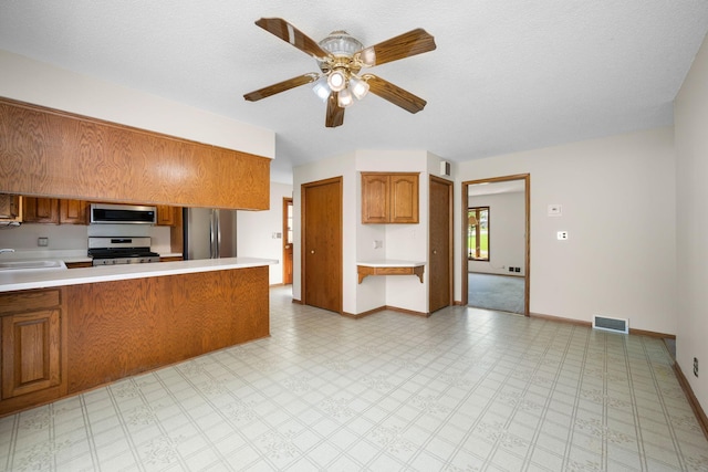 kitchen featuring stainless steel appliances, baseboards, visible vents, and brown cabinets