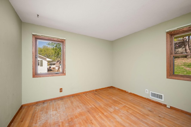 empty room featuring baseboards, light wood-type flooring, and visible vents