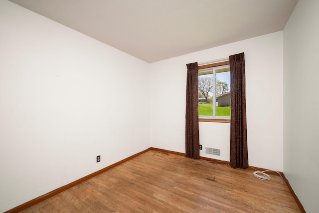 empty room featuring baseboards, light wood-type flooring, and visible vents