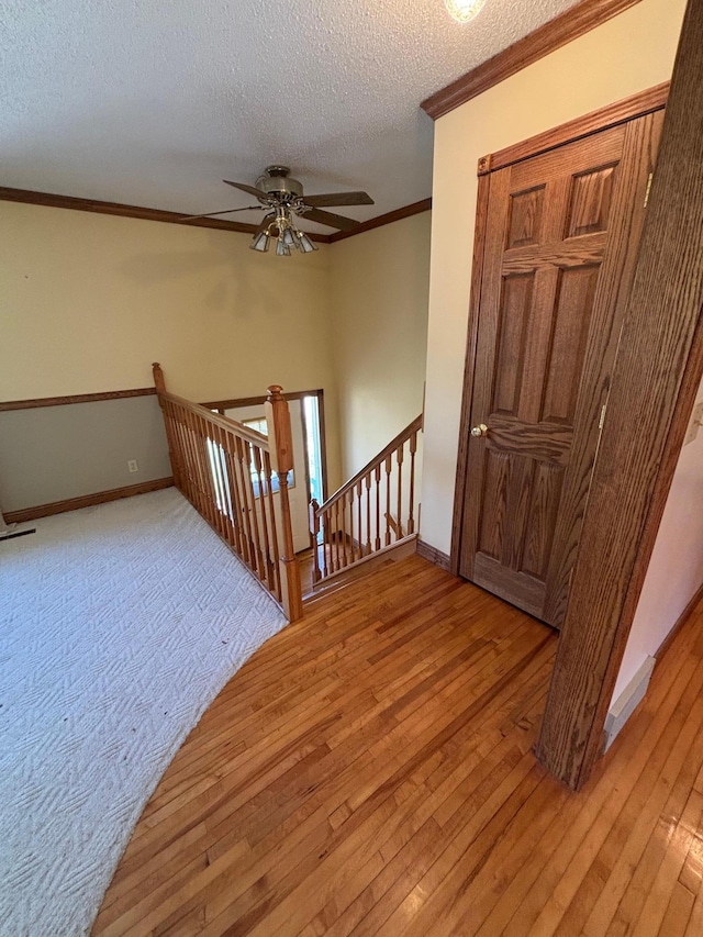 409 4th St NE, Hayfield, MN 55940 - stairway with ornamental molding, hardwood / wood-style floors, a textured ceiling, ceiling fan, and baseboards