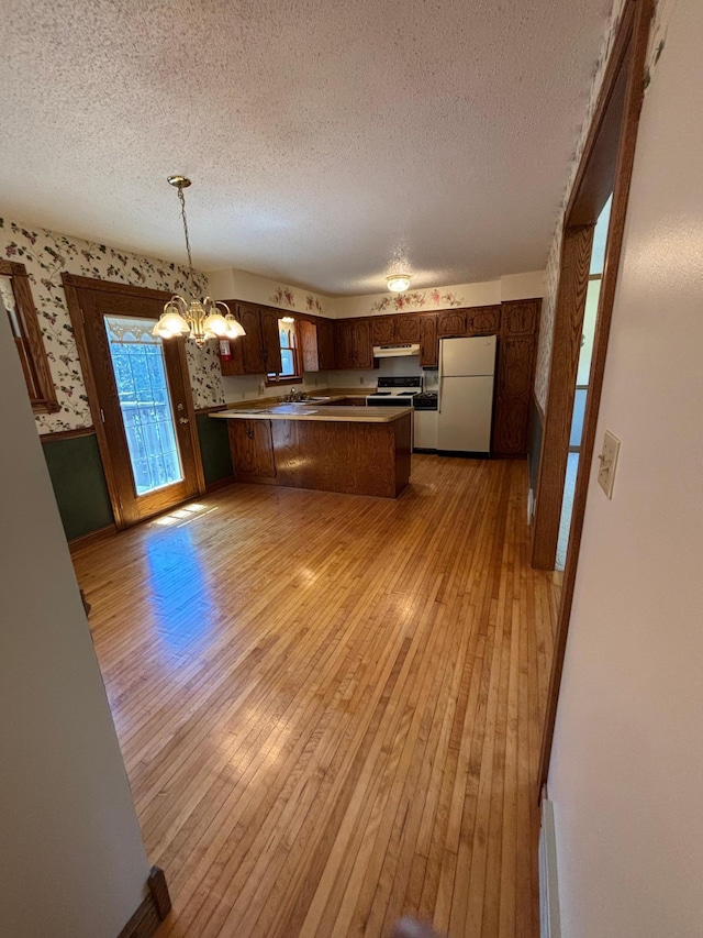 409 4th St NE, Hayfield, MN 55940 - kitchen featuring freestanding refrigerator, a textured ceiling, a peninsula, wallpapered walls, and under cabinet range hood