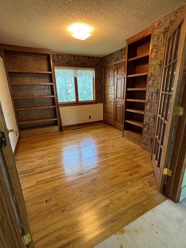 409 4th St NE, Hayfield, MN 55940 - unfurnished bedroom featuring wallpapered walls, wood finished floors, baseboards, and a textured ceiling