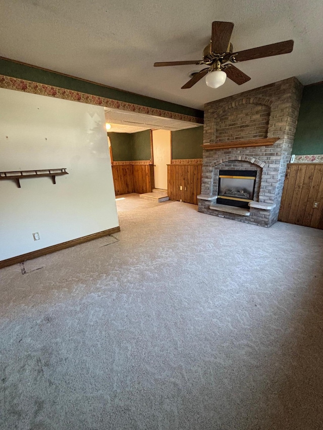 409 4th St NE, Hayfield, MN 55940 - unfurnished living room with carpet flooring, a ceiling fan, wainscoting, a textured ceiling, and a fireplace