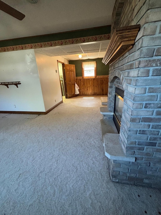 409 4th St NE, Hayfield, MN 55940 - unfurnished living room with a fireplace, a wainscoted wall, carpet floors, wood walls, and baseboards
