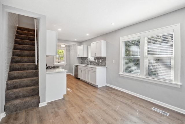3410 Russell Ave N, Minneapolis, MN 55412 - kitchen featuring appliances with stainless steel finishes, light countertops, light wood-style flooring, baseboards, and white cabinetry
