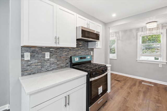 3410 Russell Ave N, Minneapolis, MN 55412 - kitchen featuring stainless steel appliances, wood finished floors, tasteful backsplash, white cabinetry, and light stone countertops