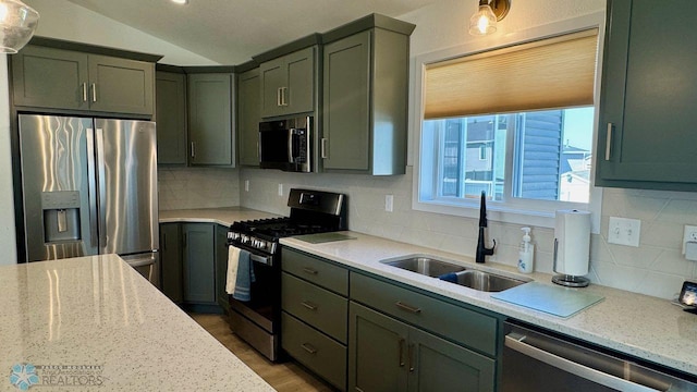 5477 11th St W, West Fargo, ND 58078 - kitchen with a sink, green cabinets, appliances with stainless steel finishes, decorative backsplash, and lofted ceiling