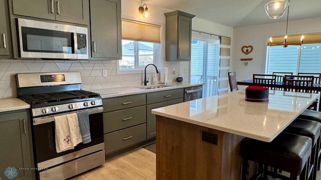 5477 11th St W, West Fargo, ND 58078 - kitchen featuring a sink, stainless steel appliances, backsplash, a center island, and light stone countertops