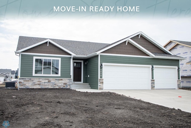 craftsman house with concrete driveway, an attached garage, a shingled roof, and stone siding