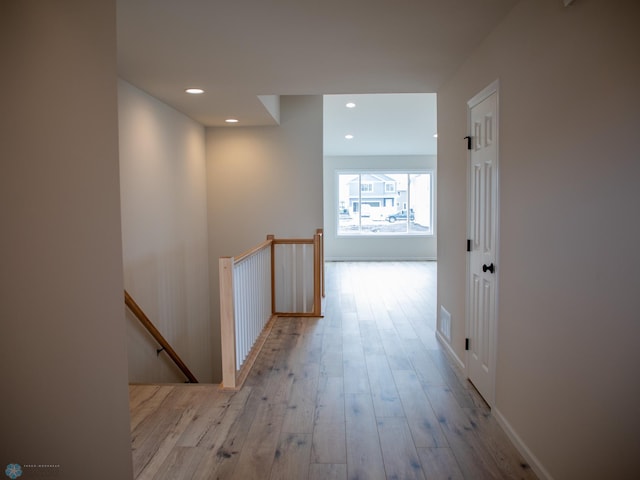 corridor with wood finished floors, an upstairs landing, baseboards, and recessed lighting